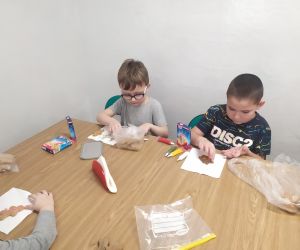 Chłopcy dekorują ciastka pisakami i posypką