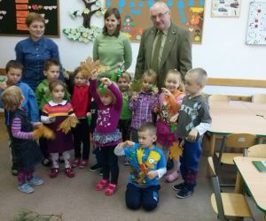 Zdjęcie grupowe: Panie nauczycielki, leśnik i dzieci, pozują do fotografii.