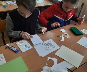 Chłopcy wycinają i przyklejają elementy na kartkę