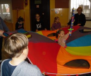 Zdjęcie przedstawia dzieci bawiące się chustą animacyjną. 