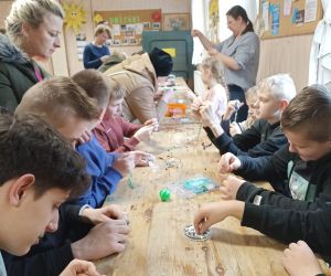 Zdjęcie przedstawia grupę młodzieży podczas warsztatów z wykonywania biżuterii.