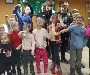 Zdjęcie przedstawia grupę dzieci pozujących do zdjęcia wewnątrz budynku.