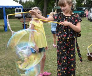 Na zdjęciu dziewczynka robi bańkę mydlaną. 