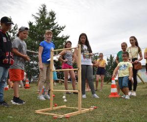 Grupa dzieci gra w grę „ladder golf” na dworze.