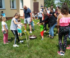 Grupa dzieci wraz z dorosłymi robi bańki mydlane.