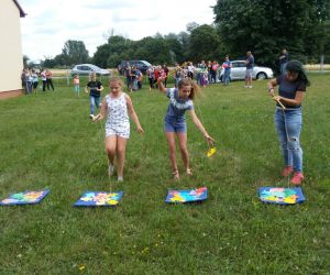 Na zdjęciu na pierwszym planie trzy dziewczynki łowią rybki zabawki za pomocą specjalnych wędek zakończonych magnesem. W oddali znajduje się grupka dzieci, które przyglądają się zabawie.