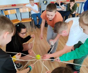 Grupa osób wewnątrz budynku, gra w zabawę integracyjną przy użycia 