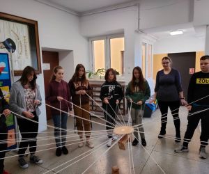 Grupa osób wewnątrz budynku, gra w zabawę integracyjną przy użycia 