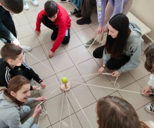 Grupa osób wewnątrz budynku, gra w zabawę integracyjną przy użycia 