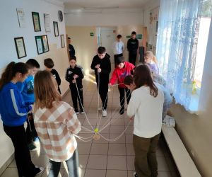 Grupa osób wewnątrz budynku, gra w zabawę integracyjną przy użycia 