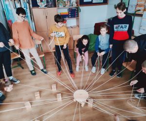 Grupa osób wewnątrz budynku, gra w zabawę integracyjną przy użycia 