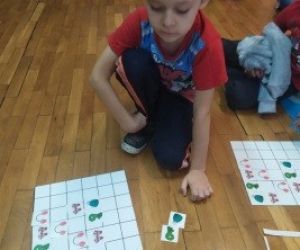 Zamyślony chłopiec siedzi na podłodze, dopasowuje elementy układanki.