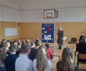 Poetka mówi do grupy siedzących dzieci