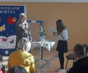 Stojąca przed poetką dziewczynka czyta z książeczki