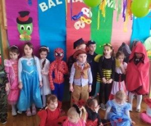 Zdjęcie grupowe, dzieci przebrane za różne postacie, stoją przy ścianie, na której jest napis; bal karnawałowy