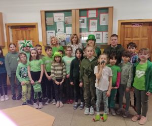 Opiekunowie i uczniowie w zielonych strojach