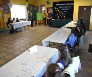 Zdjęcie przedstawia dzieci i dorosłych zgromadzonych w budynku.