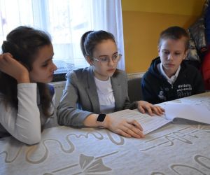 Zdjęcie przedstawia trójkę dzieci zastanawiające się nad zadaniem.