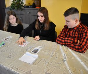 Zdjęcie przedstawia trójkę dzieci rozwiązujących zadanie.