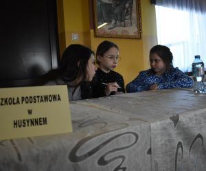 Zdjęcie przedstawia trójkę dzieci siedzących przy stole.