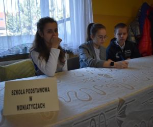 Zdjęcie przedstawia trójkę dzieci siedzących przy stole.