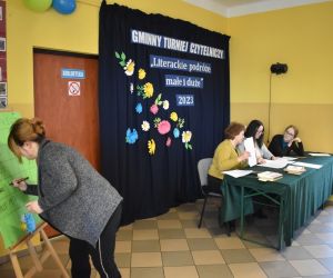 Zdjęcie przedstawia cztery osoby dorosłe jedna z nich zapisuje wynik rozgrywek na tablicy.