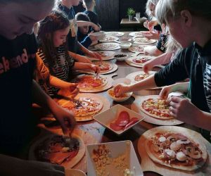 Uczniowie przy stole podczas warsztatów z pieczenia pizzy