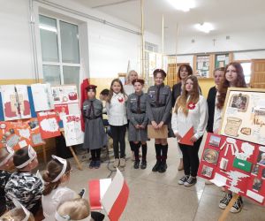 Uczennice z  panią Dyrektor i nauczycielkami na wspólnym zdjęciu, w tle prace konkursowe