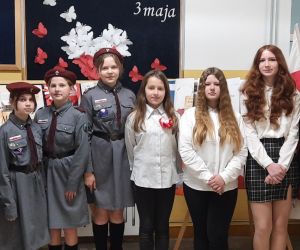 Uczennice występujące w apelu na tle gazetki okolicznościowej