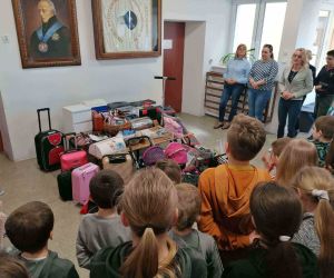 Przedmioty zastępujące plecaki przy ścianie. Dookoła nauczyciele i uczniowie