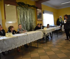 Na zdjęciu widoczne są dzieci siedzące przy stołach.