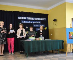 Na zdjęciu widoczne są osoby dorosłe stojące w pomieszczeniu.