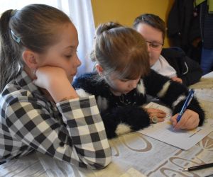 Na zdjęciu widoczne są dzieci siedzące przy stole.