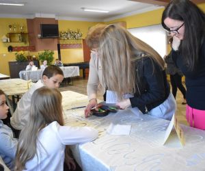 Na zdjęciu widoczne są dzieci i dorośli. Komisja ocenia rozwiązane zadania.