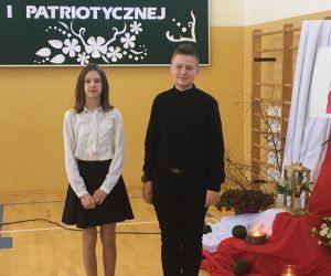 Uczeń i uczennica na tle dekoracji okolicznościowej