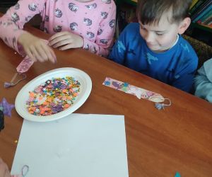 Na zdjęciu widoczne są dzieci wykonujące prace plastyczną.