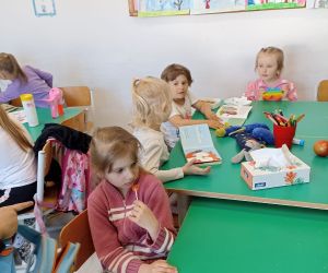 Zdjęcie przedstawia dzieci siedzące w ławkach czytające książki.