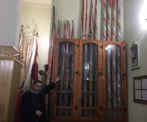 Proboszcz parafii w Tyszowcach wskazuje dłonią na zabytkowe świece umieszczone w gablocie