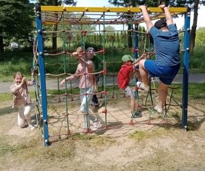 Grupa dzieci bawi się na placu zabaw znajdującym się przy Parku