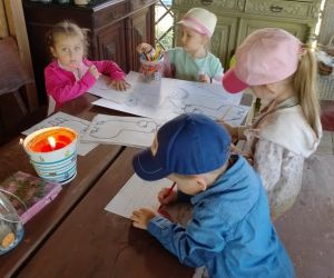 Przedszkolaki przy stole kolorują obrazki z alpakami