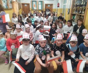 Przedszkolaki w uroczystych opaskach z godłem i z flagami Polski