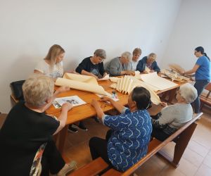 Grupa kobiet wewnatrz budynku wykonujaca rękodzieło.