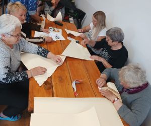 Grupa kobiet wewnatrz budynku wykonujaca rękodzieło.