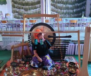 Koncert mis tybetańskich, kobieta wewnątrz budynku uderzająca w misy.