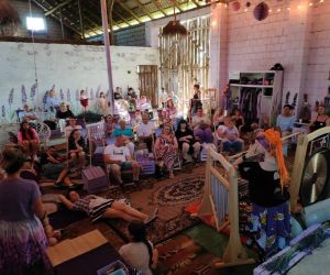 Grupa ludzi w wiejskiej stodole podczas koncertu mis tybetańskich.