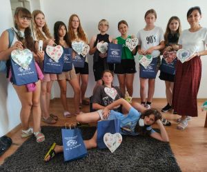 Grupa dzieci wewnątrz budynku, prezentująca wykonana prace z rękodzieła.