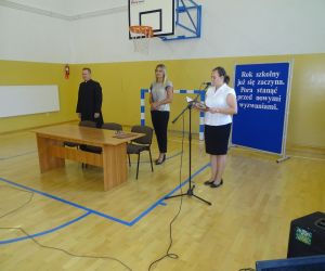 Nauczycielka, dyrektor szkoły i proboszcz parafii Czerniczyn stoją przy stole prezydialnym