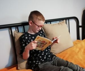 Chłopiec czytający książkę na łóżku w sypialni