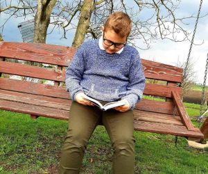 Chłopiec czytający książkę na huśtawce na podwórku