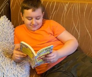 Chłopiec czytający książkę na sofie w salonie